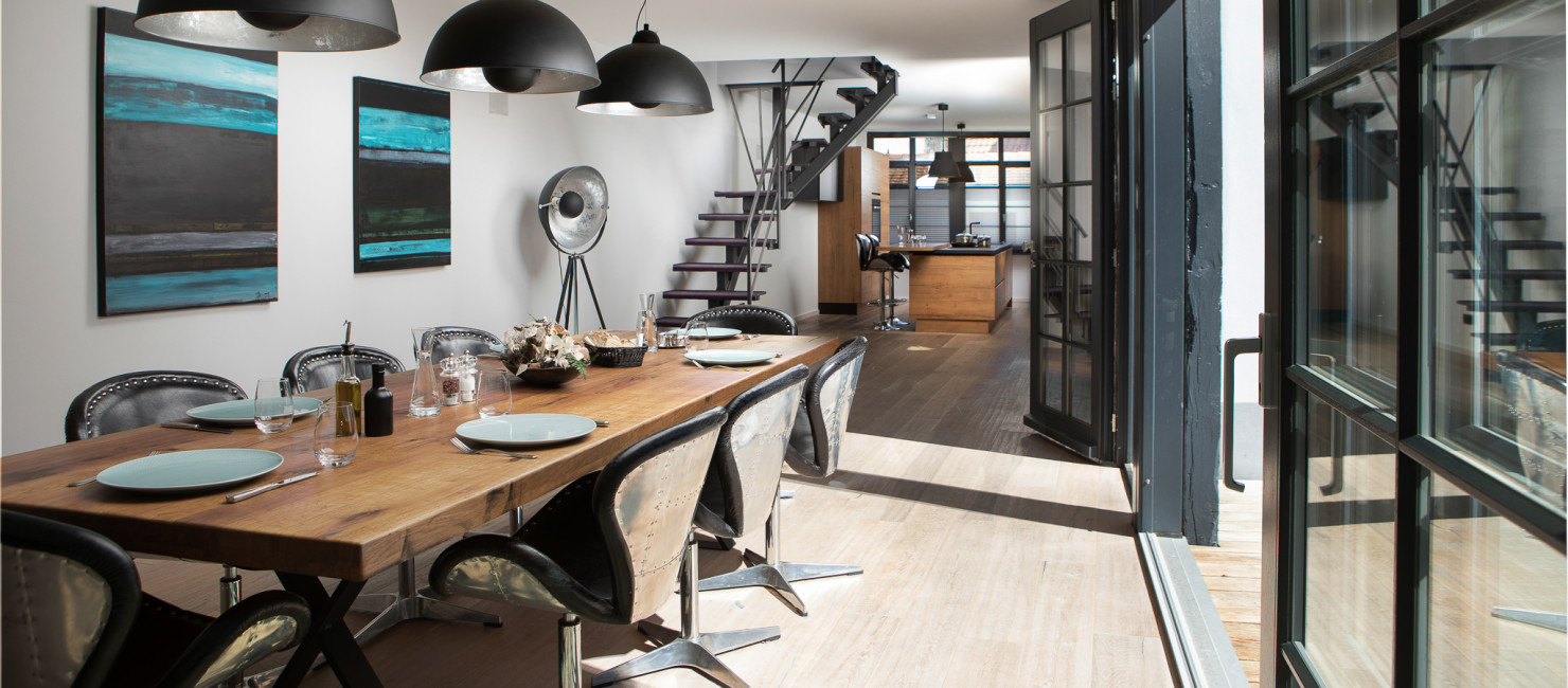 Einblick in den Essbereich des Loft 46a mit großem Holztisch, modernen Stühlen und offenem Durchgang zur Küche