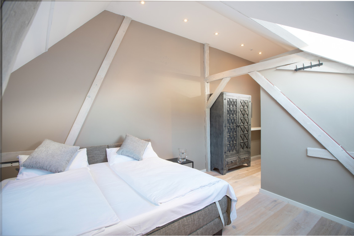 Schlafzimmer in der gemütlichen Dachschräge in hellem grau und weiß gehalten