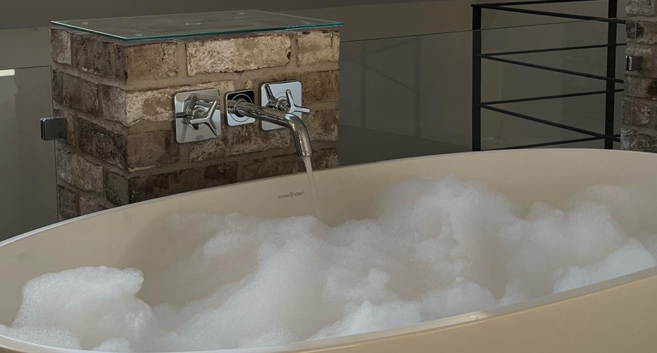 Freistehende Badewanne mit Mauersteinen und eingelassenen Schaumbad